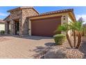 Attractive home with a tile roof, a two-car garage, desert landscaping and a paver driveway at 16229 W Jenan Dr, Surprise, AZ 85379