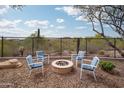Outdoor sitting area with a fire pit, desert views, and chairs with blue cushions at 27196 N 129Th Dr, Peoria, AZ 85383