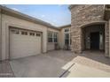 A view of the home's entrance, featuring a spacious three-car garage, a tiled entryway, and inviting front patio at 4497 E Ficus Way, Gilbert, AZ 85298