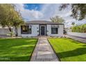 Charming single-story home with lush green lawn, stone pathway, and classic architectural details at 541 W Palm Ln, Phoenix, AZ 85003