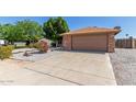 Well-maintained single-story home with a desert landscape and long driveway leading to a two-car garage at 6413 W Monte Cristo Ave, Glendale, AZ 85306