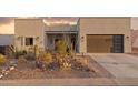 Southwestern-style home with desert landscaping, a modern garage door, and warm outdoor lighting at 9827 E Fortuna Ave, Gold Canyon, AZ 85118