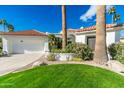 Inviting single-story home featuring lush landscaping, mature palm trees, and a convenient two-car garage at 11736 E Del Timbre Dr, Scottsdale, AZ 85259