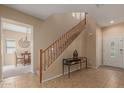 Inviting entryway with tile flooring, wood staircase, and views into the dining area at 14239 W Port Royale Ln, Surprise, AZ 85379