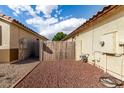 The backyard shows a red rock landscape enclosed by block wall, a wooden gate, and the home's exterior at 15328 W Memory Ln, Surprise, AZ 85374