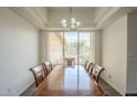 Bright dining room with tray ceilings, a large window, and a wooden table with chairs at 17790 N 66Th Ln, Glendale, AZ 85308
