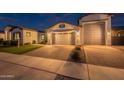 Exterior shot of a well-lit home showcasing its manicured lawn and inviting facade at twilight at 21617 S 229Th Way, Queen Creek, AZ 85142