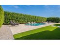 Backyard view showcases a pristine pool, lush greenery, and modern lounge furniture for relaxation at 21617 S 229Th Way, Queen Creek, AZ 85142