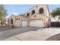Inviting home exterior with neutral stucco, arched windows, three-car garage, and expansive driveway at 3557 S Halsted Ct, Chandler, AZ 85286