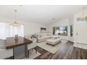 Bright living room featuring dark wood flooring, a decorative chandelier, and comfortable white furniture at 5153 W Topeka Dr, Glendale, AZ 85308