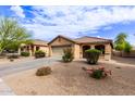 Inviting single-story home showcasing desert landscaping, a two-car garage, and a charming covered porch entrance at 749 E Desert Moon Trl, San Tan Valley, AZ 85143