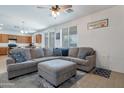 Spacious living room featuring a plush sectional sofa, an ottoman, and an open floor plan with a view into the kitchen at 10221 W Puget Ave, Peoria, AZ 85345