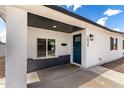 Inviting covered front entrance with dark blue door and stylish exterior lighting fixture at 1038 N 78Th Pl, Scottsdale, AZ 85257