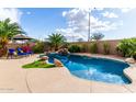 Backyard pool with unique stone waterfall features, lush tropical landscaping, and sunny lounge area at 12526 S 176Th Ave, Goodyear, AZ 85338