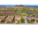 Expansive aerial view showcasing the home with solar panels nestled in a lush, vibrant community near desert mountains at 13336 W Via Caballo Blanco --, Peoria, AZ 85383