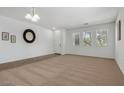 Bright living room featuring neutral carpet, white walls, and natural light from three windows at 18325 W Port Au Prince Ln, Surprise, AZ 85388