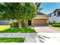 Charming single-Gathering home with a well-kept lawn, mature tree, and brick driveway leading to a two-car garage at 3023 E Arabian Dr, Gilbert, AZ 85296