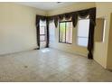 An empty living room features tan walls, tile floors, and large windows with brown curtains at 4843 E Estevan Rd, Phoenix, AZ 85054