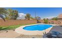 A backyard with a sparkling pool surrounded by a putting green and block wall, ideal for relaxation and recreation at 5432 N Ormondo Way, Litchfield Park, AZ 85340