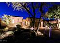 A beautifully lit home exterior at night with desert landscaping and a circular driveway at 6936 E Whispering Mesquite Trl, Scottsdale, AZ 85266