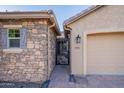 Close-up of home's entry with stone accents, decorative iron gate and security door, and a side-entry two-car garage at 10846 E Quartet Ave, Mesa, AZ 85212
