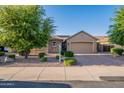 Charming single-story home featuring desert landscaping, lush trees, and a paver driveway leading to a spacious two-car garage at 10846 E Quartet Ave, Mesa, AZ 85212