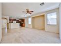 Spacious carpeted living room with a ceiling fan and kitchen access at 14214 W Ventura St, Surprise, AZ 85379