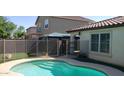 Backyard with a sparkling blue pool, artificial grass, and a covered patio for outdoor entertaining at 16155 N 171St Dr, Surprise, AZ 85388