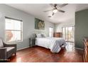 Well-lit bedroom with hardwood floors, neutral paint, a ceiling fan, and balcony access at 16616 E Gunsight Dr # 114, Fountain Hills, AZ 85268