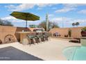 Covered outdoor bar area with seating, desert plants, and a stucco privacy wall, perfect for entertaining at 16876 W Stevenage St, Surprise, AZ 85374