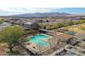 Aerial view of a community pool, covered seating and tennis courts, against a mountain backdrop at 18171 W Daley Ln, Surprise, AZ 85387