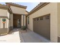 Tan home with a wooden door, a brown garage door, and the house number displayed at 27315 N 83Rd Dr, Peoria, AZ 85383