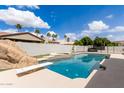 Backyard swimming pool featuring diving board, rock waterfall, and spa with palm trees in background at 3528 E Decatur St, Mesa, AZ 85213