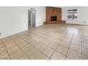 Bright living room with a brick fireplace, neutral tile flooring, and access to other rooms at 4247 N 101St Ave, Phoenix, AZ 85037