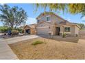 View of the home's facade, spacious driveway, desert landscaping, and mature tree at 4559 E Sierrita Rd, San Tan Valley, AZ 85143
