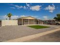 Tan, single story home features gravel landscaping, a patch of green grass, and a single car carport at 1064 S 97Th St, Mesa, AZ 85208