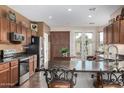 Spacious kitchen with dark wood cabinets, granite countertops, an island with a breakfast bar, and stainless steel appliances at 13051 W Black Hill Rd, Peoria, AZ 85383