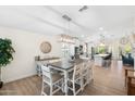Bright dining room with a wooden table, white chairs, and modern lighting, open to the kitchen at 14241 N 56Th Pl, Scottsdale, AZ 85254