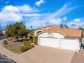 A sunny single-story home with a red tile roof, lush landscaping and a large two car garage at 14241 N 56Th Pl, Scottsdale, AZ 85254