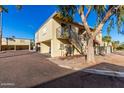 Exterior of condo with covered parking, wrought iron staircase, mature trees, and desert landscaping on a bright sunny day at 14261 N Oakwood Ln, Fountain Hills, AZ 85268