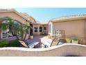 Private courtyard with stone fountain, lounge chairs, brick patio, and mature landscaping at 15061 W Pinchot Ave, Goodyear, AZ 85395