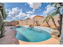 Lush backyard oasis featuring a private pool with a stone waterfall, tropical landscaping, and clear blue water at 15856 W Calavar Rd, Surprise, AZ 85379