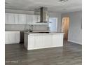 Bright kitchen with white cabinets, spacious island, stainless steel range hood, and wood-look tile flooring at 18828 N 17Th Dr, Phoenix, AZ 85027