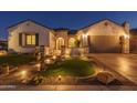 Well-lit home exterior with manicured lawn and inviting entrance at dusk at 26673 W Ponderosa Ln, Buckeye, AZ 85396