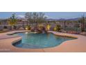Inviting pool features rock waterfall, custom lighting, and desert landscaping at 26673 W Ponderosa Ln, Buckeye, AZ 85396