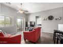 Bright living room with plush red seating, ceiling fan, and sliding glass doors to balcony at 343 N 169Th Ave, Goodyear, AZ 85338