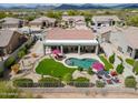 Stunning aerial view of a backyard oasis with a sparkling pool, lush lawn, covered patio, and firepit area at 4607 E Sierra Sunset Trl, Cave Creek, AZ 85331