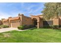 Beautiful single-story home with a tile roof, arched entryway, and landscaped yard at 9039 E Winchcomb Dr, Scottsdale, AZ 85260