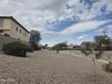 Desert landscaping on hillside with sidewalk and view of neighborhood beyond at 16810 W Portland St, Goodyear, AZ 85338