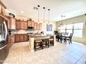 Bright kitchen with stainless steel appliances, granite countertops, island seating, and wood cabinets at 20525 W Hamilton St, Buckeye, AZ 85396